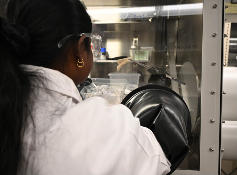 Handling air-sensitive battery materials inside an argon glovebox.