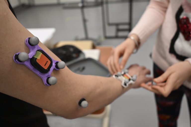 Attaching motion capture markers to a participant's arm.