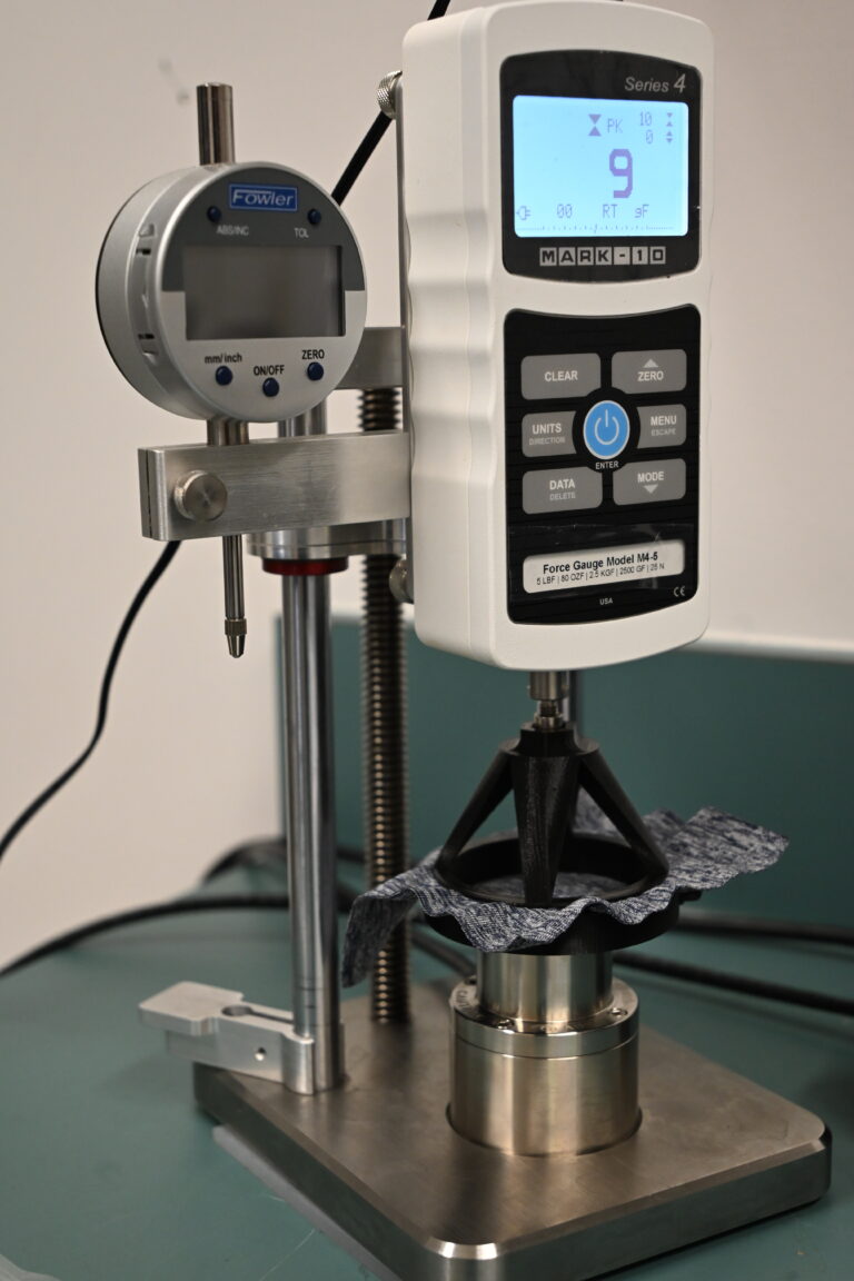 Testing fabric strength with a digital force gauge.